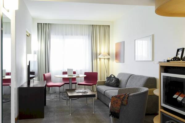 Innenraum des Novotel London West Hotels mit Wohnzimmer, Tisch und Stühlen.