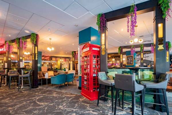 Innenansicht der Bar im Novotel London West mit roten Telefonzellen, blauen Stühlen und Marmorboden.