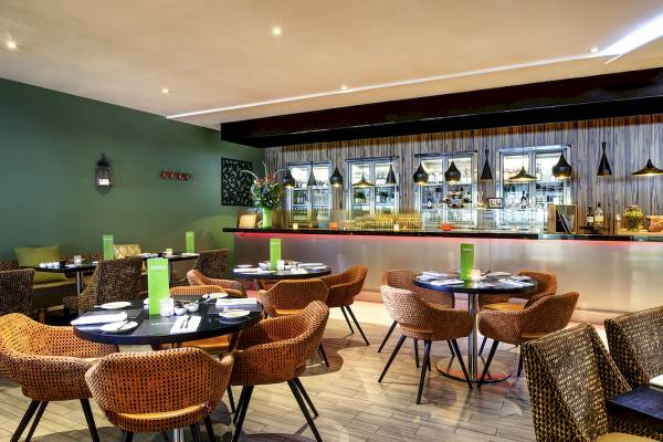 Innenbereich des Novotel London West Restaurants mit Tischen, Stühlen und einer Bar.