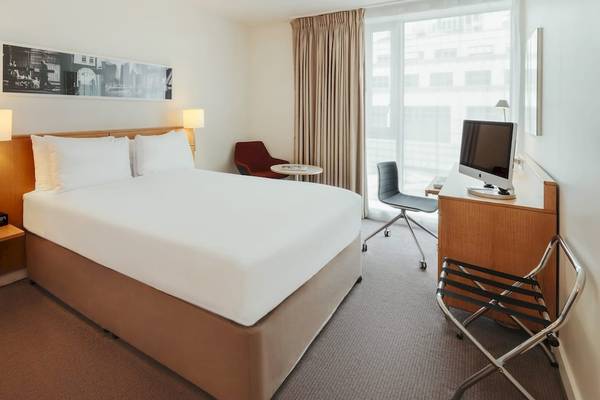 Hotelzimmer von DoubleTree by Hilton Tower of London mit Bett, Schreibtisch und Fenstern.
