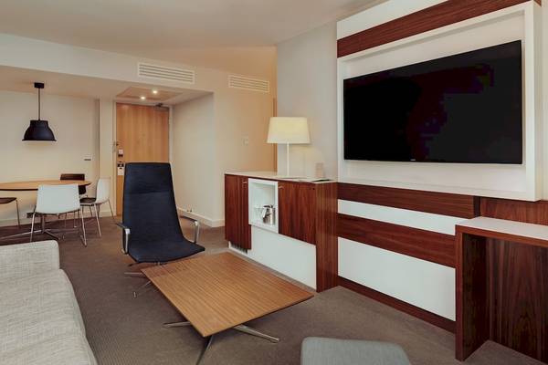 Innenansicht einer Suite im DoubleTree by Hilton Tower of London mit Fernseher, Schreibtisch und Möbeln.
