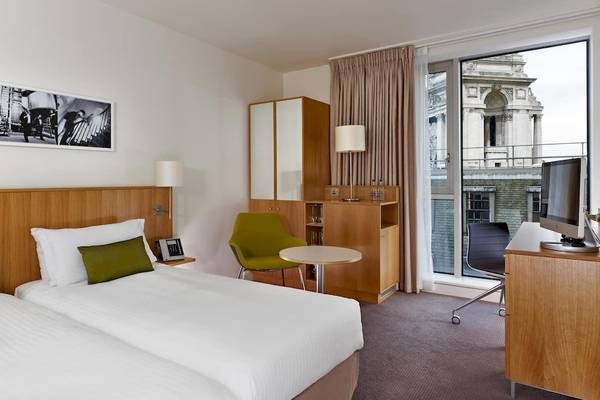 Doppelzimmer im DoubleTree by Hilton Tower of London mit zwei Betten, grünen Kissen und einem Blick auf die Stadt.