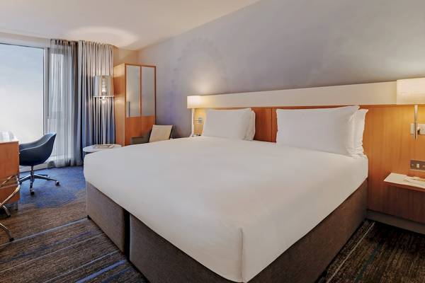 Doppelzimmer im DoubleTree by Hilton Tower of London Hotel mit Doppelbett, Schreibtisch, Stuhl und Fenstern.