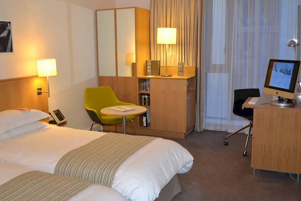 Doppelzimmer im DoubleTree by Hilton Tower of London mit zwei Betten, Schreibtisch und Sessel.