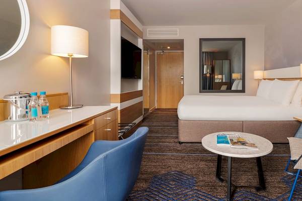 Doppelzimmer im DoubleTree by Hilton Tower of London Hotel mit Schreibtisch, Lampe, Fernseher, Bett und Spiegel.