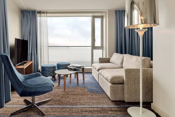 Wohnbereich im DoubleTree by Hilton Tower of London mit einem Sofa, einem Fernseher und einem Schreibtisch.
