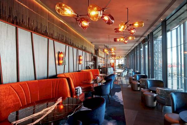 Innenansicht des Restaurants im DoubleTree by Hilton Tower of London mit orangenen Sitzbänken und blauen Stühlen.