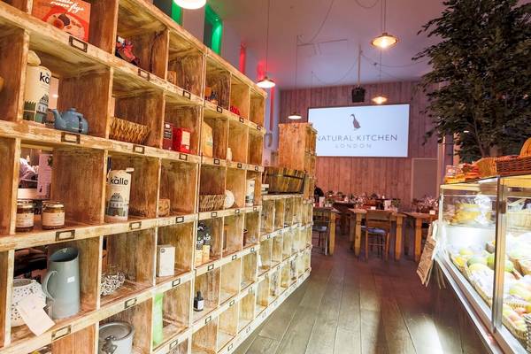 Innenansicht des Natural Kitchen London im DoubleTree by Hilton Tower of London mit Regalen, Tischen und einer Tafel