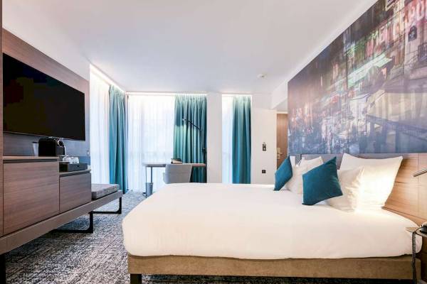 Hotelzimmer im Novotel Paris Centre Bercy mit Doppelbett, Fernseher und Schreibtisch.