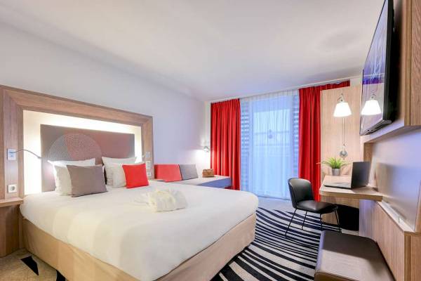 Hotelzimmer im Novotel Paris Centre Bercy mit einem Bett, Sofa, Schreibtisch und Fernseher.