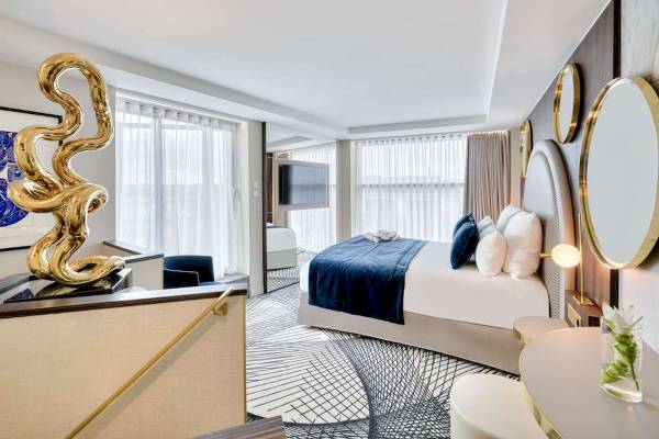 Innenansicht des Schlafzimmers im Novotel Paris Centre Bercy mit goldener Skulptur, Bett, Möbeln und Fenstern.