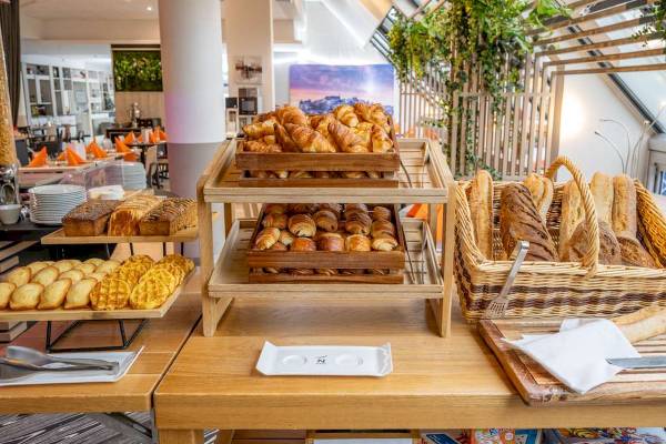 Frühstücksbuffet im Novotel Paris Centre Bercy mit Croissants, Brötchen und Brot in Holzkörben.