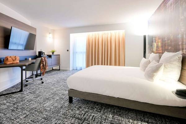 Innenansicht eines Hotelzimmers im Novotel Paris Centre Bercy mit Bett, Schreibtisch und Fernseher.