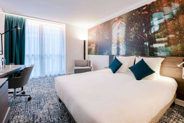 Hotelzimmer im Novotel Paris Centre Bercy mit großem Bett, Schreibtisch und modernen Möbeln.