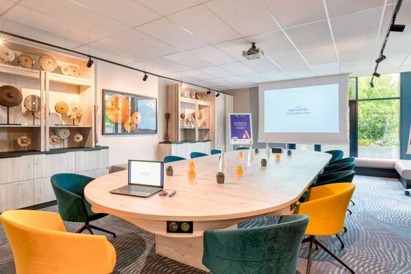 Konferenzraum im Novotel Paris Centre Bercy mit Laptop, Projektor und Kunstwerken.