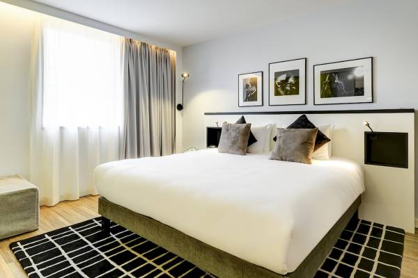 Schlafzimmer im Novotel Paris Centre Bercy mit einem Bett, Kissen und drei gerahmten Bildern an der Wand.