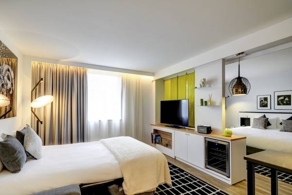 Innenansicht des Schlafzimmers im Novotel Paris Centre Bercy mit zwei Betten, Fernseher und Dekoartikeln.