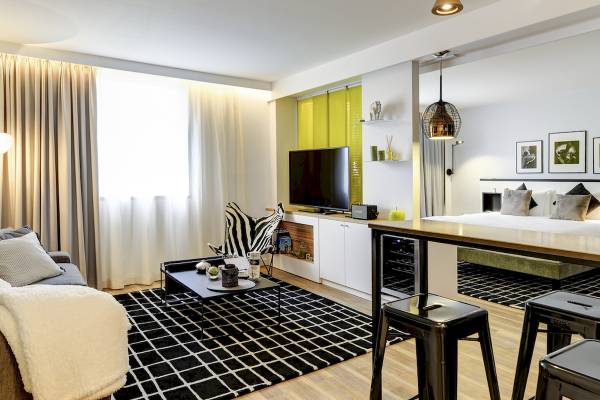 Wohnzimmer des Novotel Paris Centre Bercy mit Fernseher, Couch, Tisch und Stühlen.