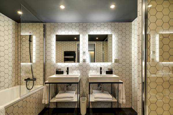 Badezimmer im Novotel Paris Centre Bercy mit zwei Waschbecken, Badewanne und hexagonalen Fliesen.