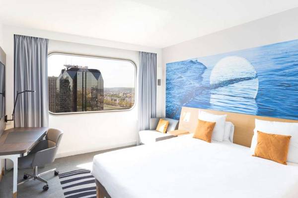 Innenansicht eines Hotelzimmers im Novotel Paris Tour Eiffel mit Blick auf die Stadt.