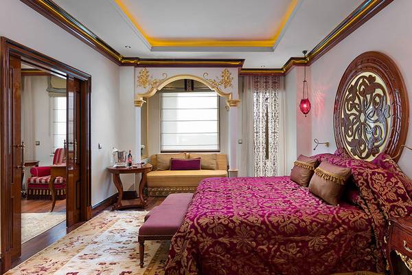 Luxuriöses Hotelzimmer im Titanic Mardan Palace mit einem großen roten Bett, einem Couch, und einem großen Spiegel.