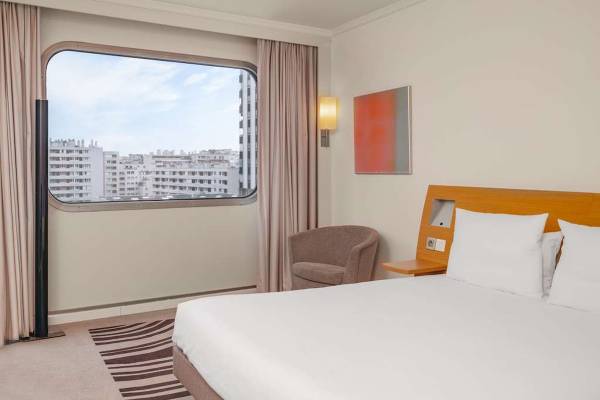 Innenansicht eines Zimmers im Novotel Paris Tour Eiffel mit Blick auf die Stadt.