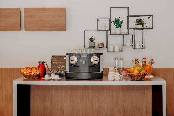Frühstücksbuffet im Novotel Paris Tour Eiffel mit Kaffeemaschine, Obst und Getränken.