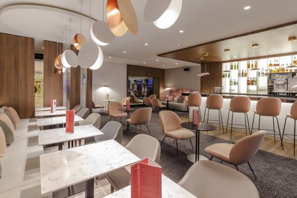 Innenbereich des Novotel Paris Tour Eiffel Restaurants mit modernen Möbeln, Marmortischen und Bar.