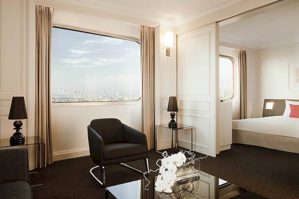 Innenansicht eines Hotelzimmers im Novotel Paris Tour Eiffel mit Blick durch das Fenster auf die Stadt.