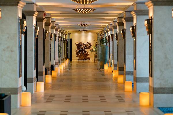 Innenbereich des Titanic Mardan Palace Hotels mit langem Flur, dekorativen Kerzen und einer großen Skulptur.