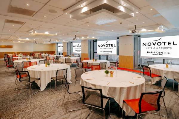 Besprechungsraum im Novotel Paris Tour Eiffel mit runden Tischen und Stühlen.