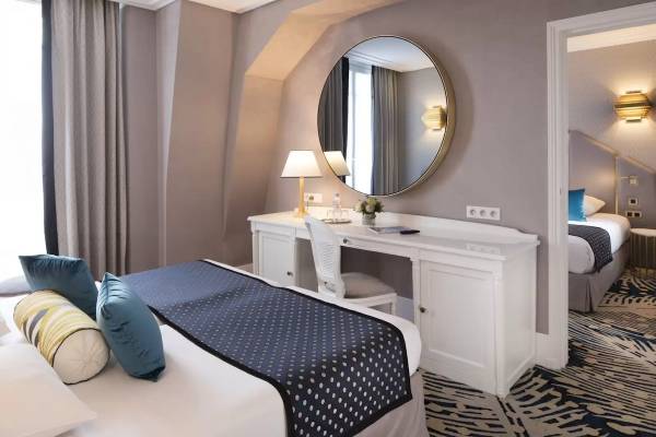 Victor Hugo Paris Kléber Hotelzimmer mit Bett, Schreibtisch und Dekoblumen.