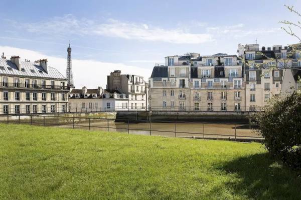 Stadtlandschaft von Paris mit dem Eiffelturm im Hintergrund, umgeben von Gebäuden und einem Fluss.
