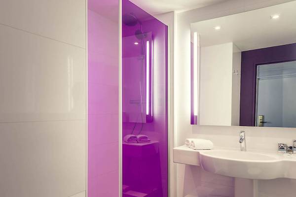 Badezimmer im Mercure Paris Bercy Bibliothèque Hotel mit violetter Dusche und weißem Waschbecken