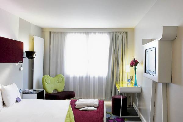 Hotelzimmer im Mercure Paris Bercy Bibliothèque mit einem Bett, einem grünen Stuhl und einem Fernseher.