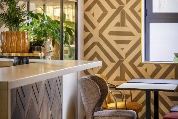 Innenansicht der Bar des Mercure Paris Bercy Bibliothèque Hotels mit Pflanzen, Stühlen und Tischen.