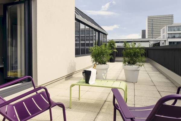 Terrasse des Mercure Paris Bercy Bibliothèque Hotels mit grünem Tisch, Flasche und Gläsern.