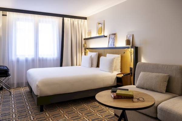 Hotelzimmer im Mercure Paris Bercy Bibliothèque mit Bett, Sofa, Tisch und Büchern.