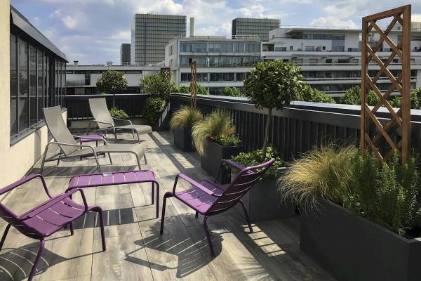 Terrasse mit Lounge-Stühlen und Pflanzen im Freien, Blick auf die Stadt