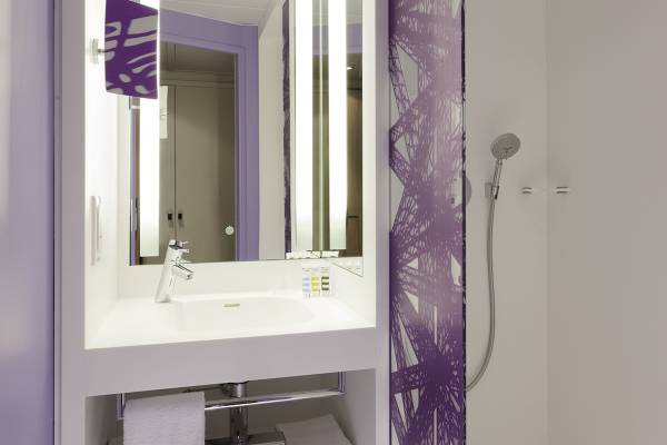 Badezimmer im Mercure Paris Centre Tour Eiffel Hotel mit violetten Wandmustern und einer Dusche.