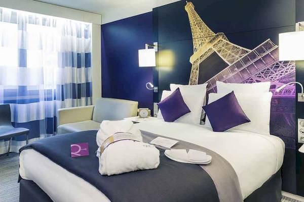 Hotelzimmer im Mercure Paris Centre Tour Eiffel mit Bett, Kissen, Eiffelturm Wandbild und Fenster.