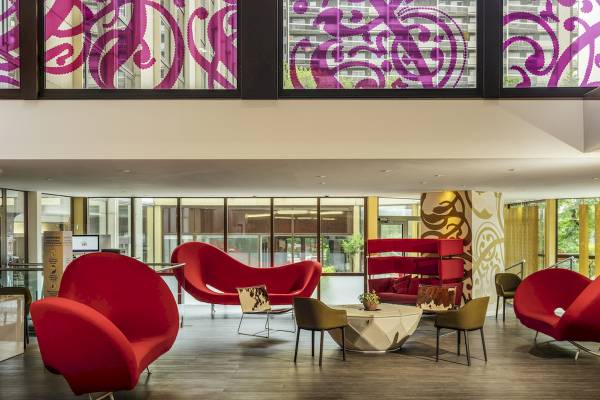 Lobby des Mercure Paris Centre Tour Eiffel Hotels mit roten Möbeln und bunten Fenstern.