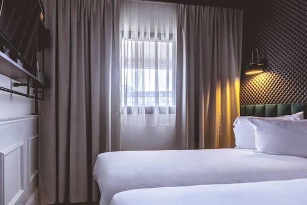 Doppelbettzimmer im ReMIX Hotel mit Fernseher, Fenster und Vorhängen.