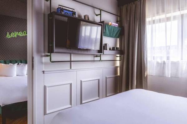 Ein Hotelzimmer von The ReMIX Hotel mit zwei Betten, einer grünen Wand und einer Fernsehmontage an der Wand.
