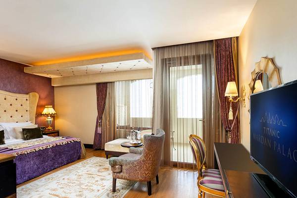 Schlafzimmer im Titanic Mardan Palace Hotel mit großem Bett, Möbeln und Fernseher.