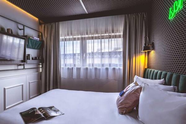 Innenansicht eines Zimmers im ReMIX Hotel mit einem Bett, Fernseher und Fenster.