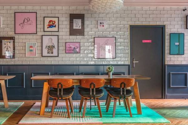 Innenbereich des ReMIX Hotels mit Tisch, Stühlen, Wandkunst und gefliester Wand.