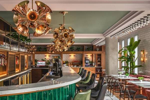 Innenansicht der Bar im ReMIX Hotel mit grüner Theke, hängenden Kronleuchtern und braunen Stühlen.
