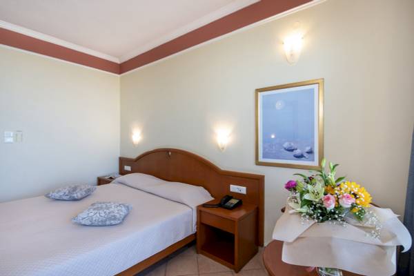 Doppelzimmer im Hydramis Palace Beach Resort mit Bett, Nachttisch, Telefon und Blumenvase.