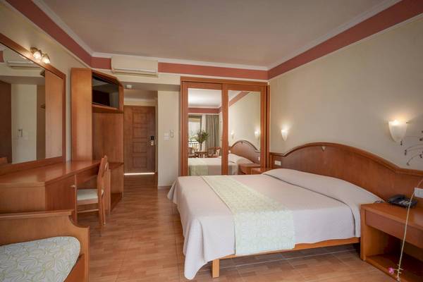 Innenansicht eines Zimmers im Hydramis Palace Beach Resort mit Bett, Schreibtisch und Spiegel.